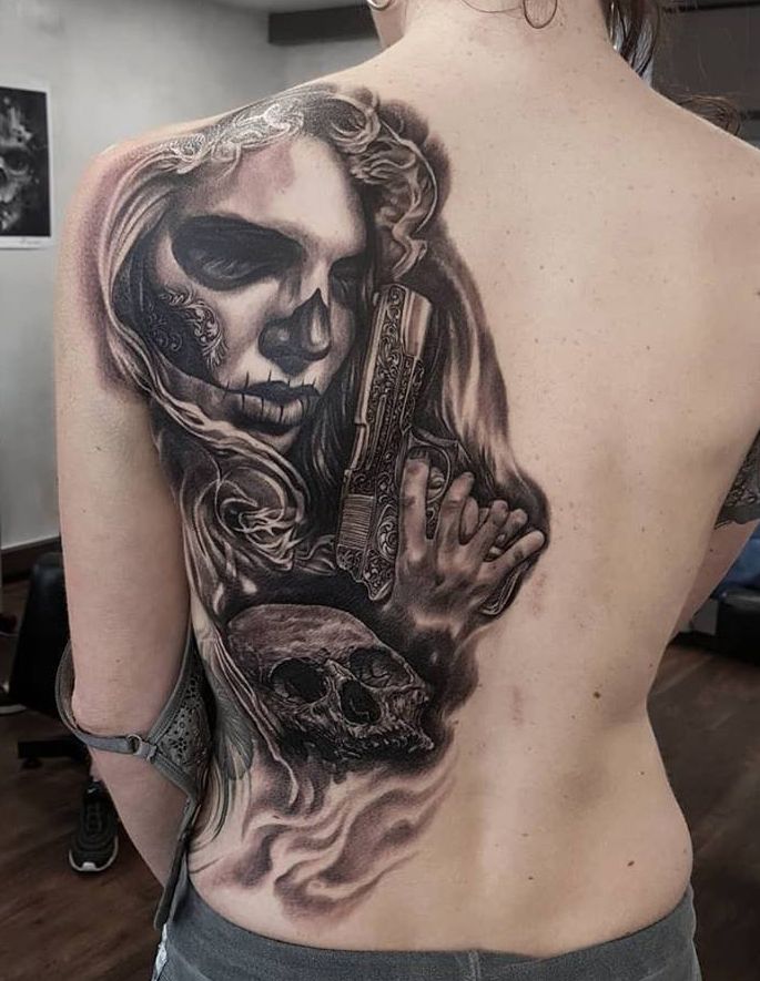 a woman with a skull and a gun on her back