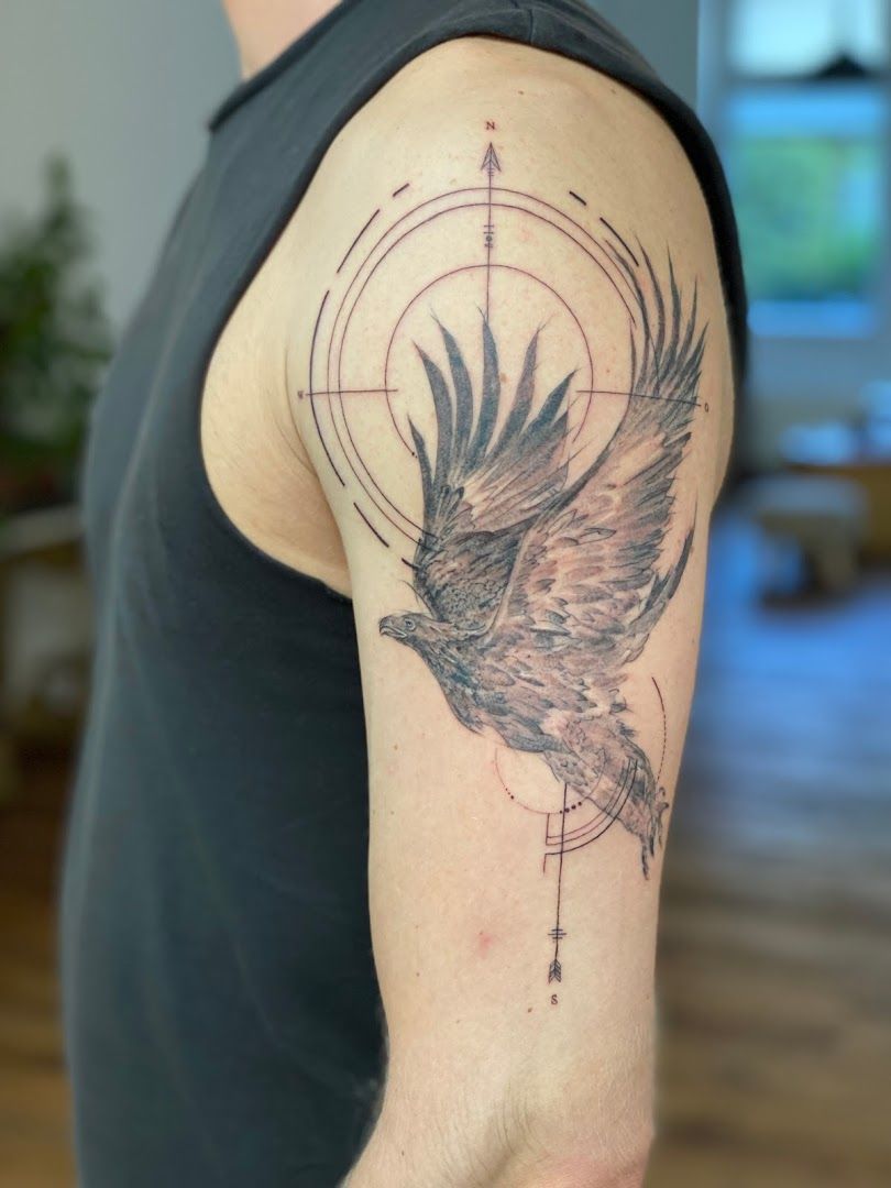 a narben tattoo of a bird with a compass on the arm, freising, germany