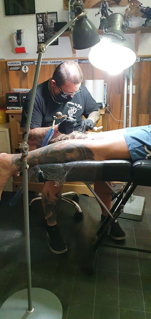 a man is sitting in a chair with a cover-up tattoo on his leg, mayen-koblenz, germany