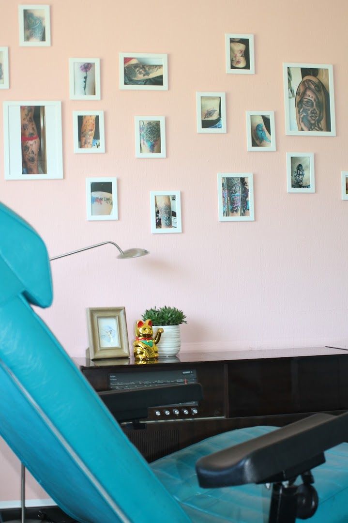 a blue chair in front of a pink wall with pictures on it