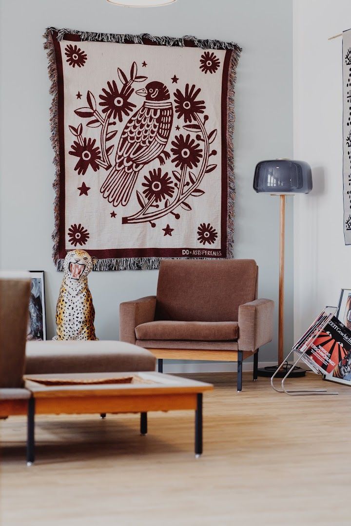 a living room with a couch, chair and tapestry