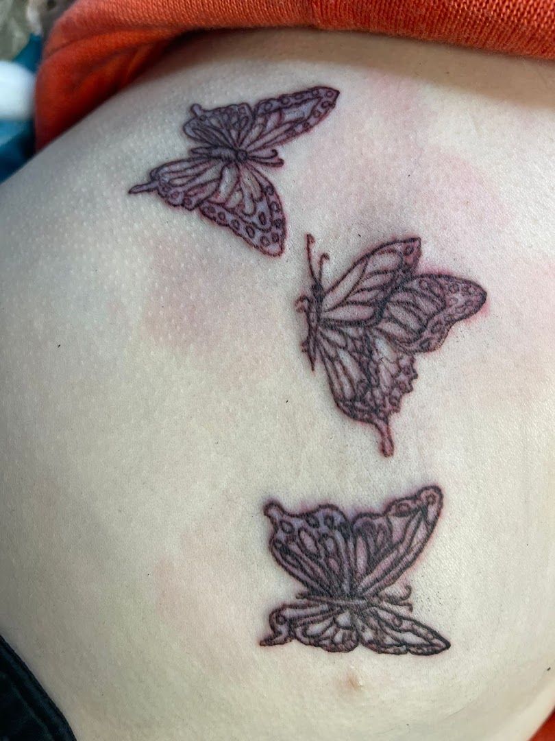 a woman's back with a trashpolka tattoos of three butterflies, goslar, germany