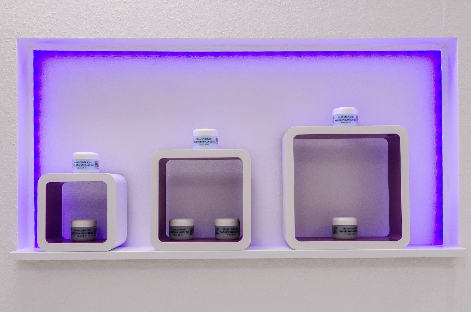 a white shelf with two bottles and a purple light