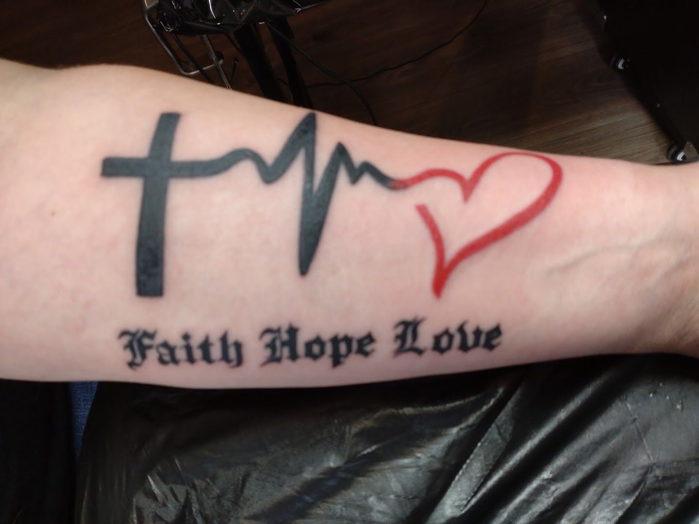 a blackwork tattoo with a heart and the word faith, esslingen, germany