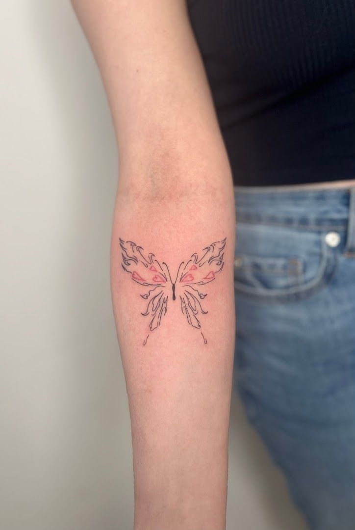 a woman's arm with a small trashpolka tattoos of a butterfly, berlin, germany