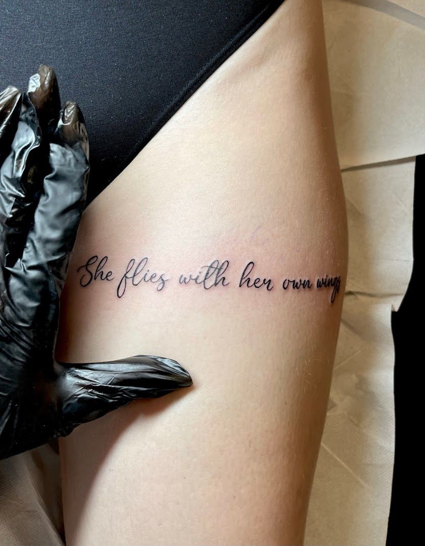 a woman's thigh with a narben tattoo saying, she is with her own, aschaffenburg, germany