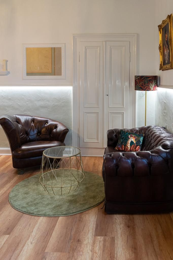 a living room with a brown leather chair and a green rug
