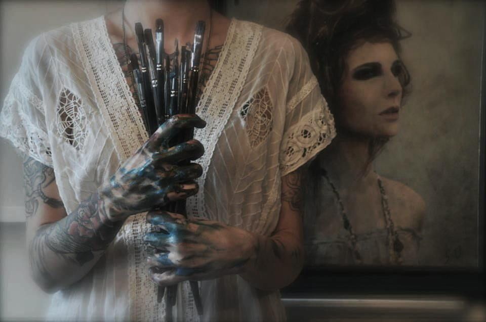 a woman holding a bunch of paint brushes