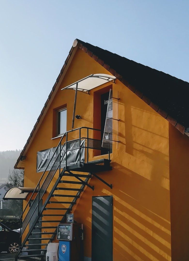 a yellow house with a black roof and stairs