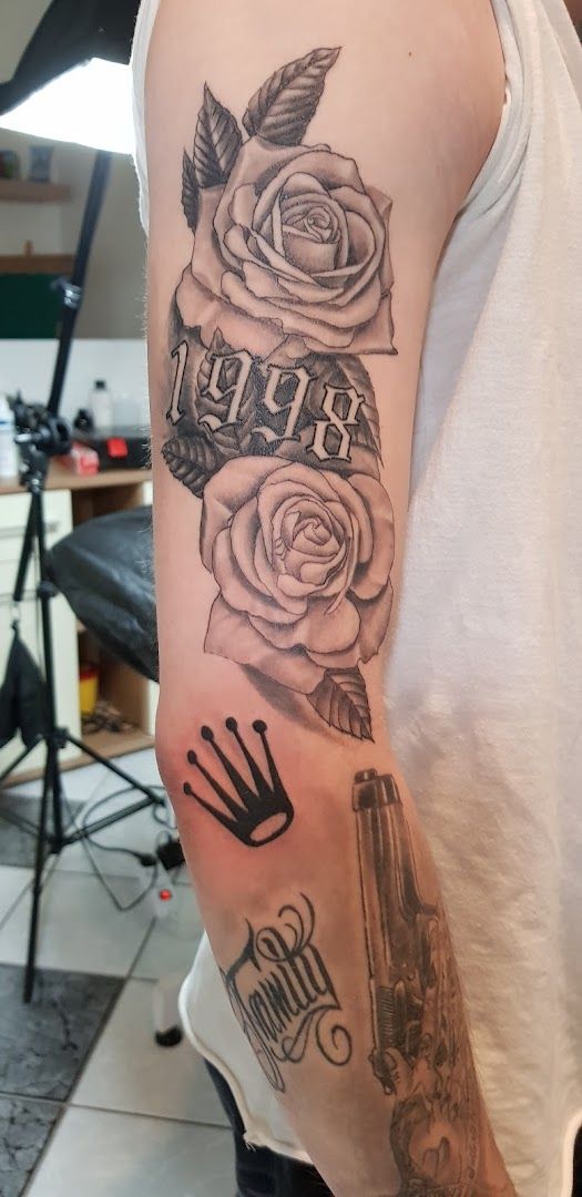 a man with a gun and roses on his arm