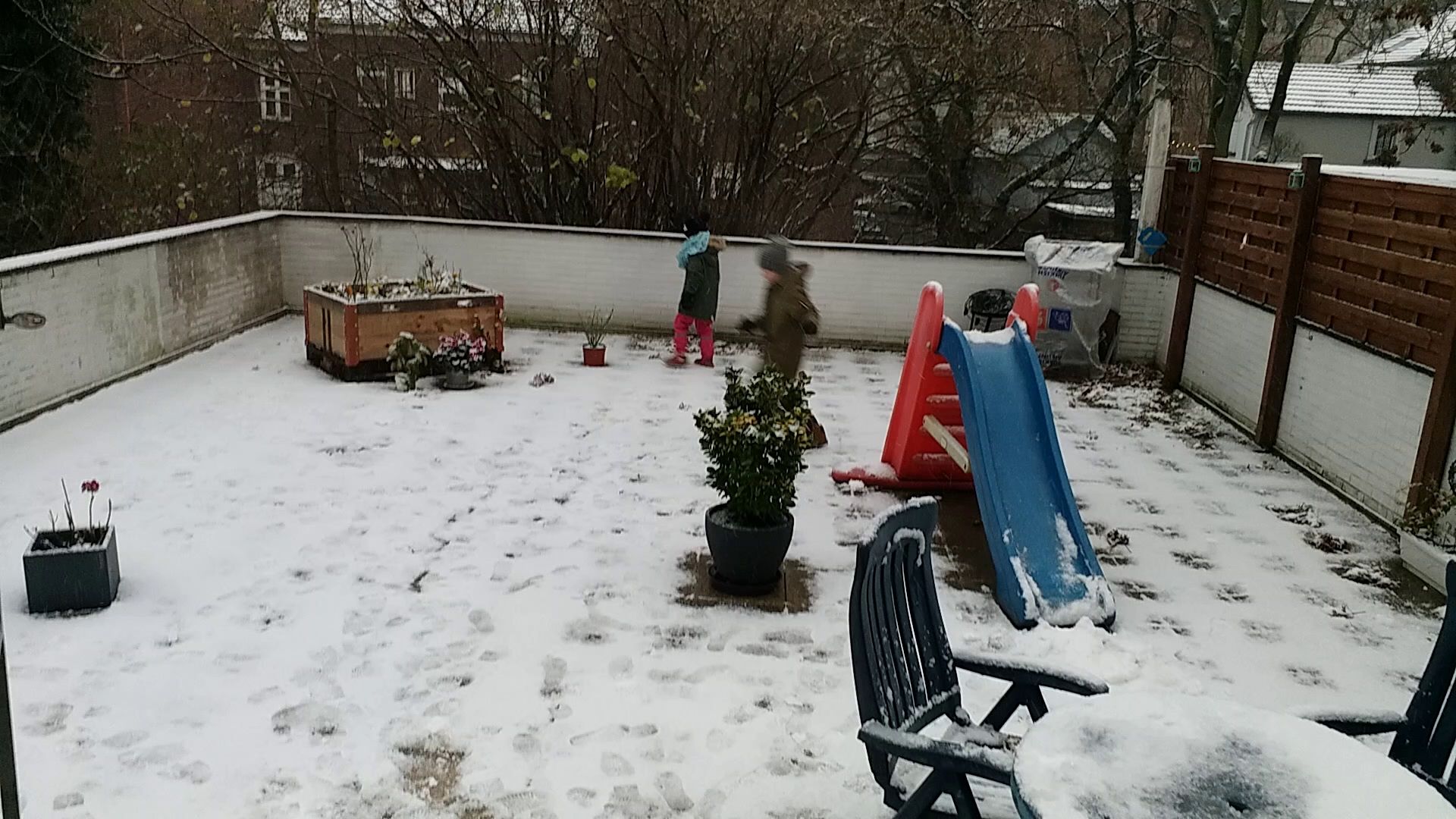 a backyard with snow on the ground and a chair