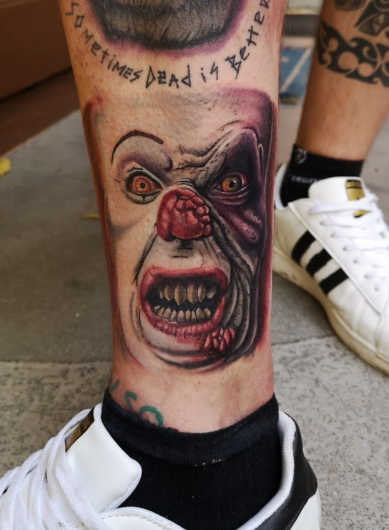 a blackwork tattoo of a clown with a clown face on his leg, neumarkt, germany