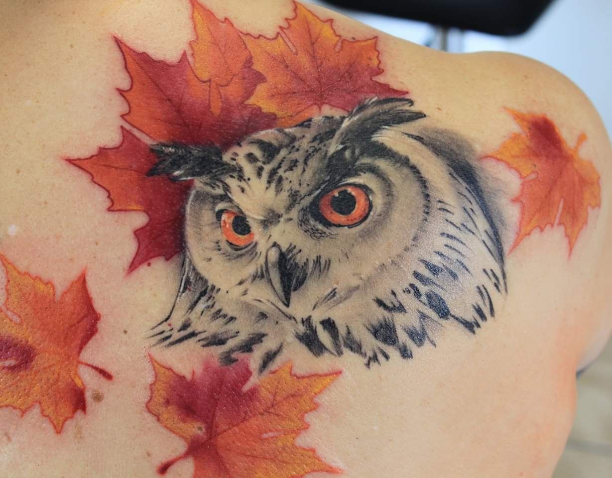 an owl with a red eye and leaves on its back