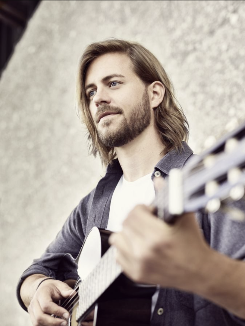 a man playing a guitar in front of a wall