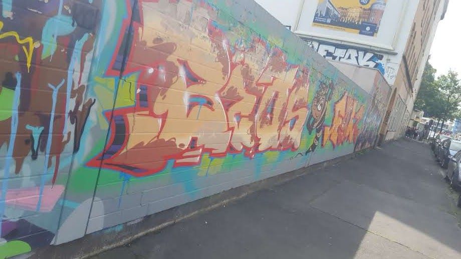 a wall with many different colored graffitis on it