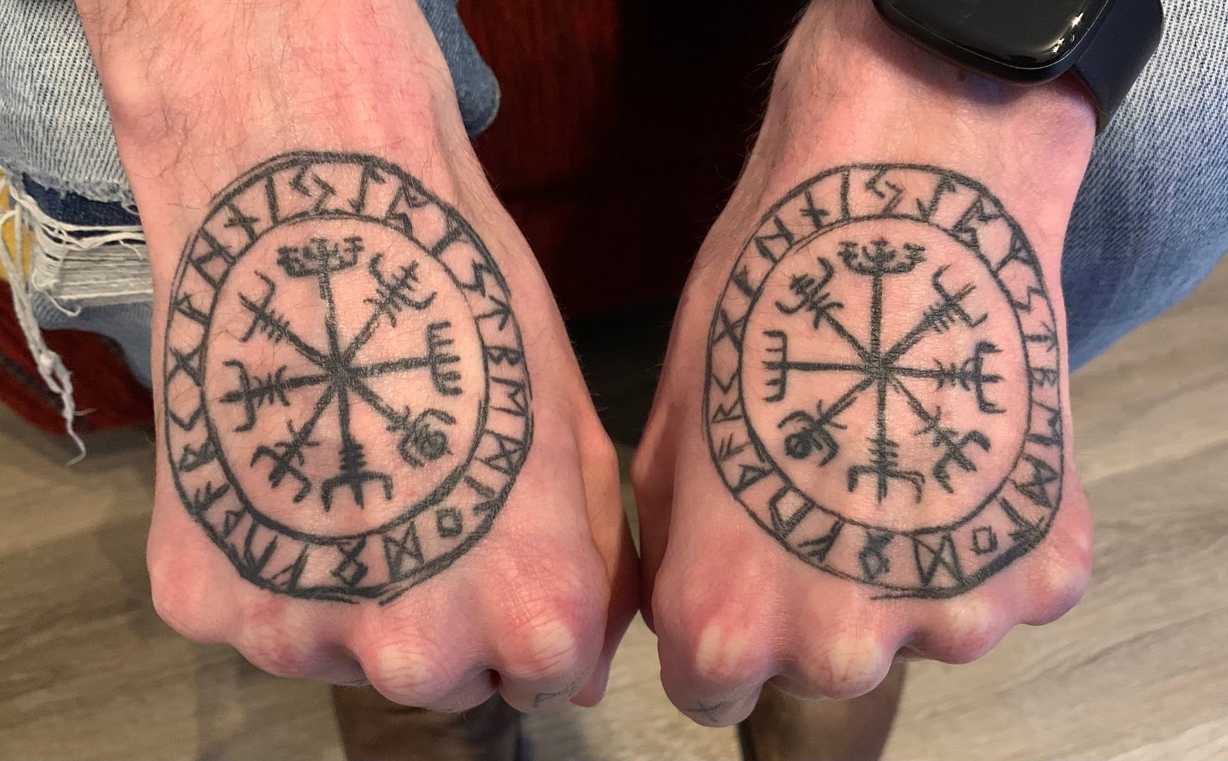 two men's hands with viking symbols on them