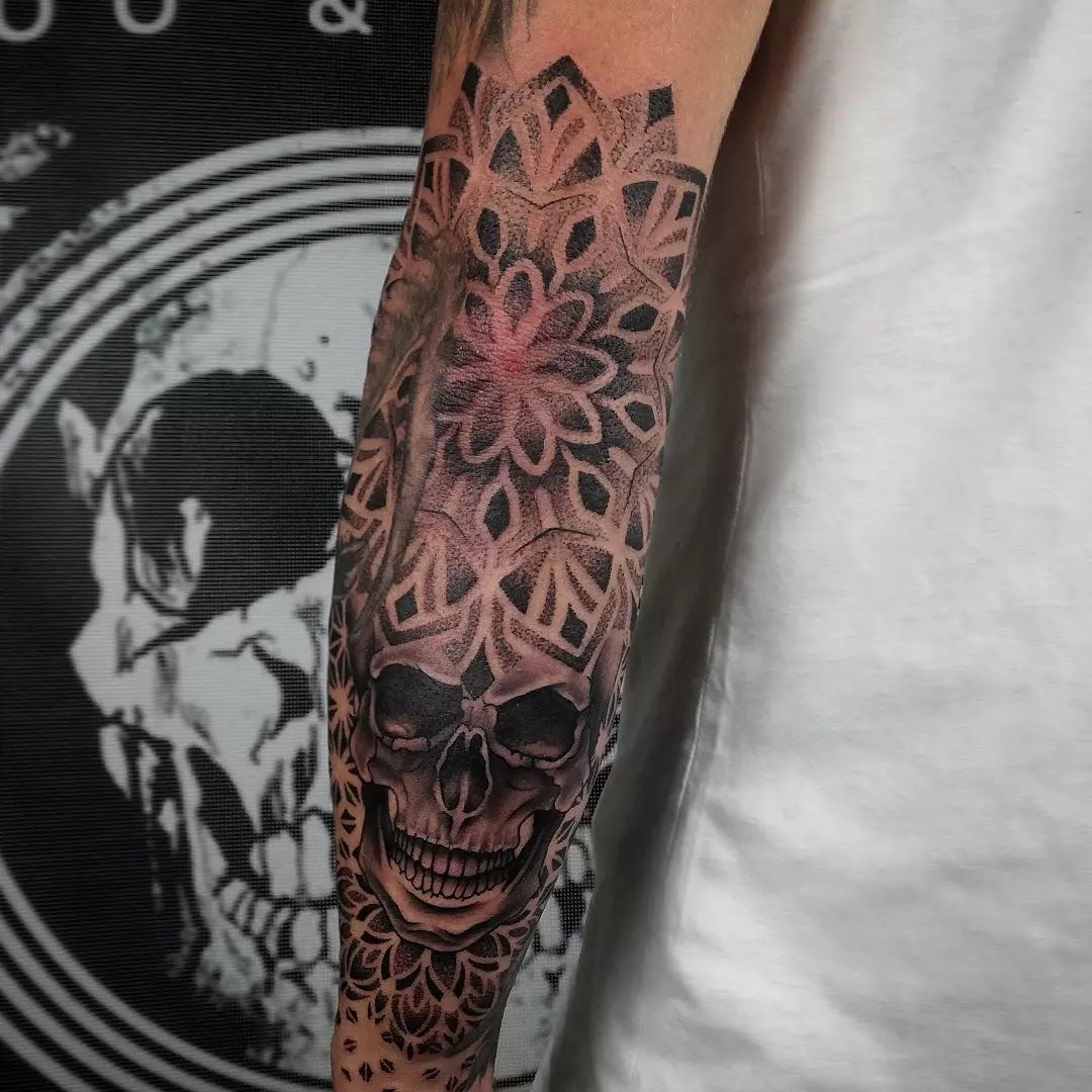 a man's forearm with a skull and flowers on it