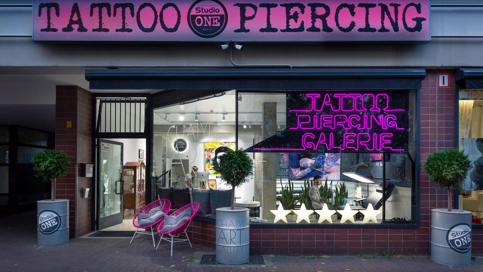 a pink neon sign on the front of a blackwork tattoo shop, berlin, germany