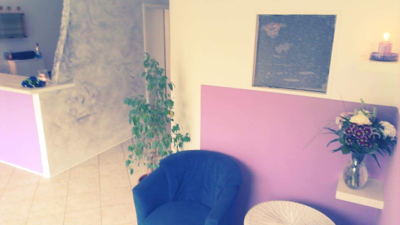 a blue chair in a room with a pink wall