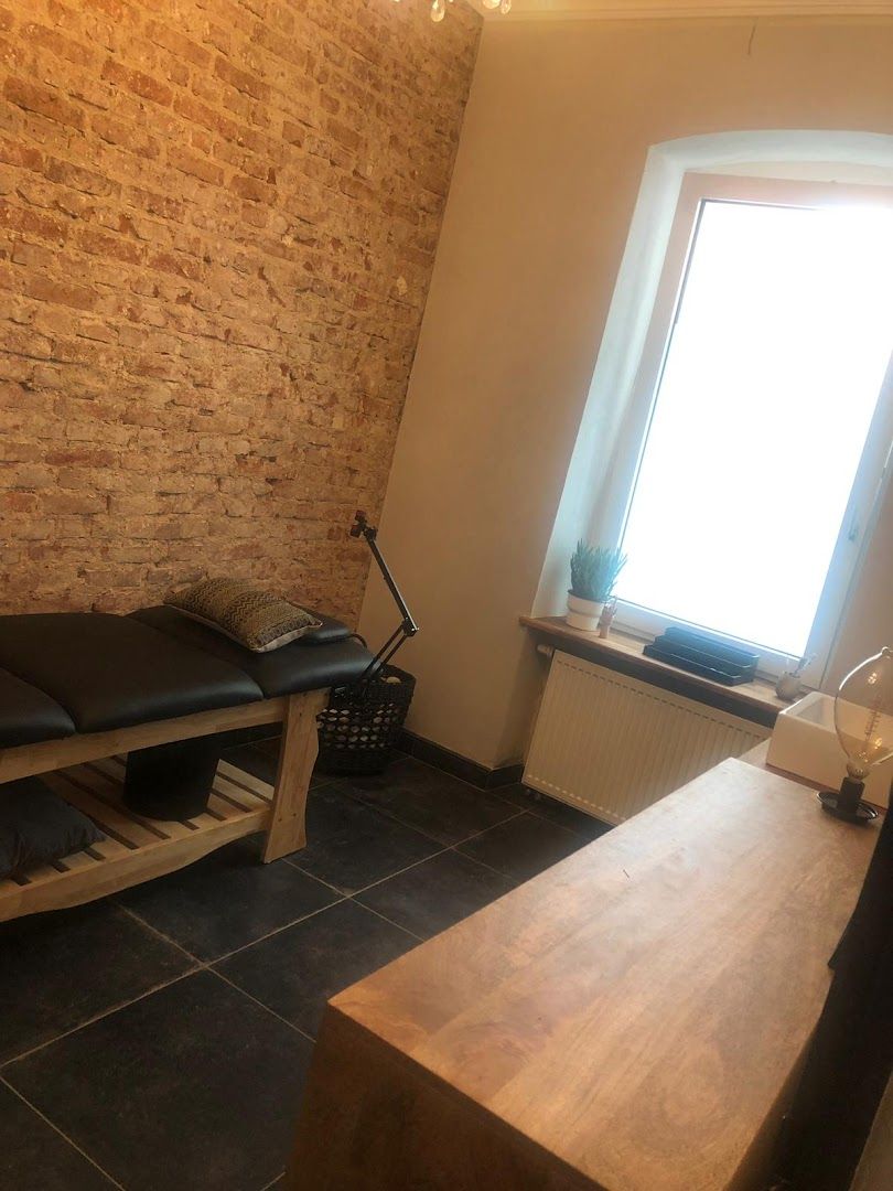 a massage room with a wooden bench and a brick wall