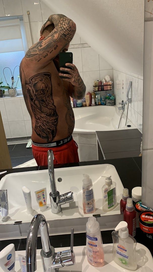 a man with cover-up tattoos on his back is taking a selfie, wesel, germany