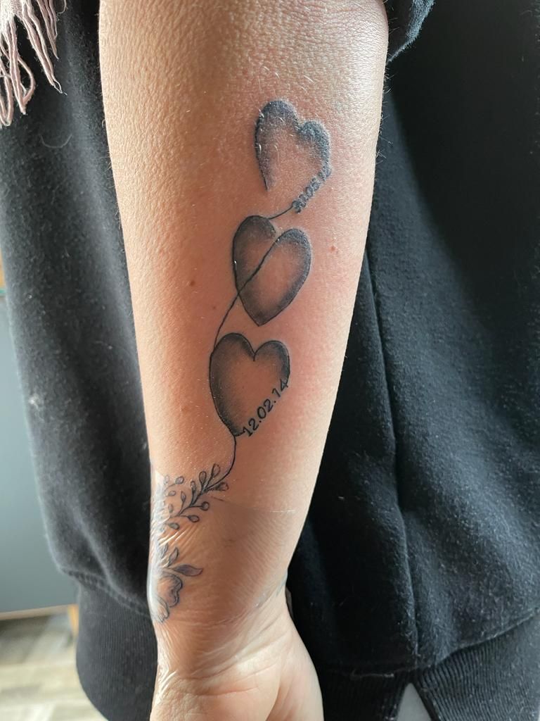 a woman's arm with a trashpolka tattoos of a heart and a flower, goslar, germany