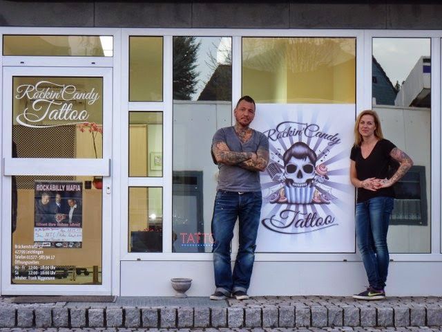 two people standing outside of a building with a sign