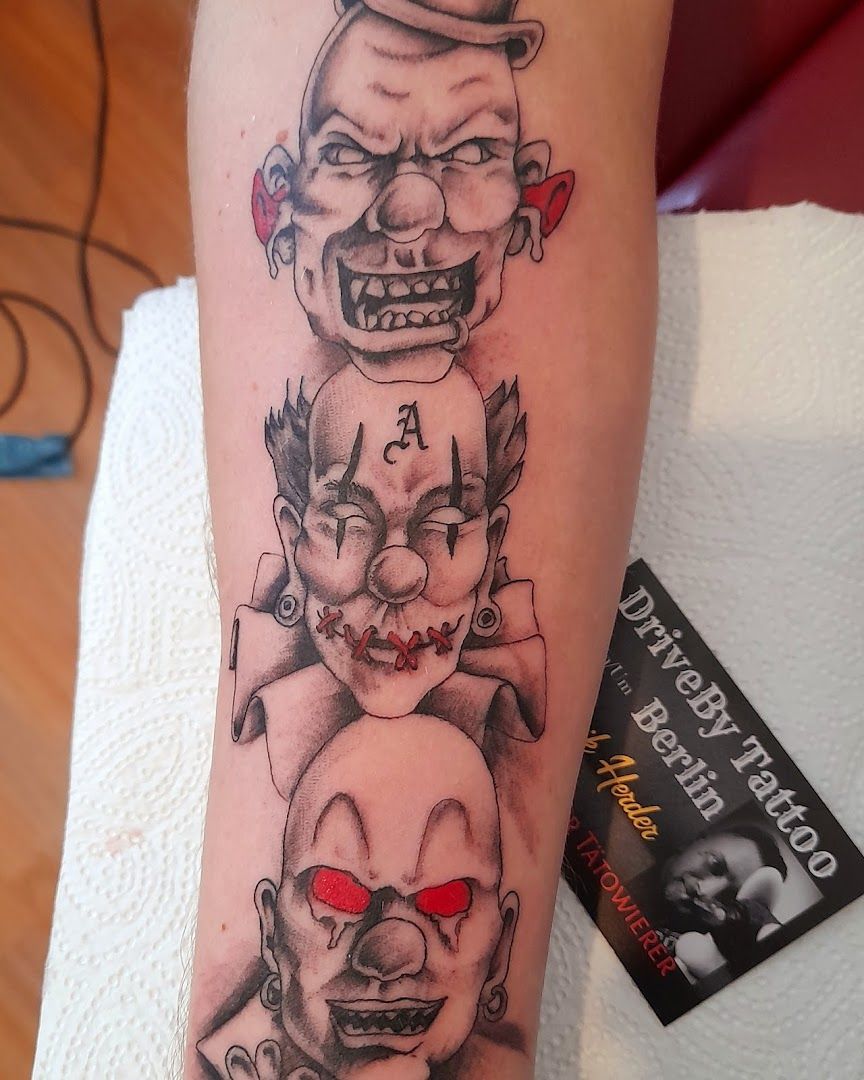 a narben tattoo of three clowns with a red heart on their arm, berlin, germany