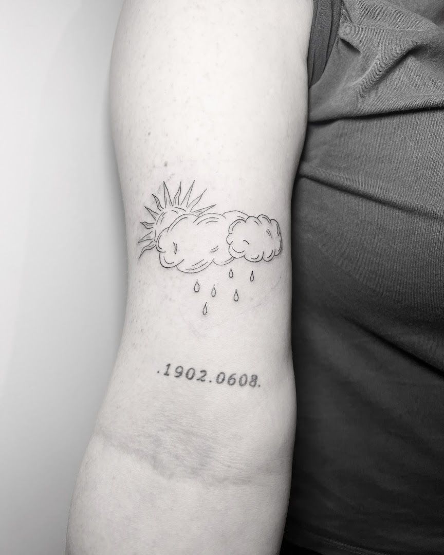 a woman's arm with a narben tattoo of a cloud and sun, ludwigsburg, germany