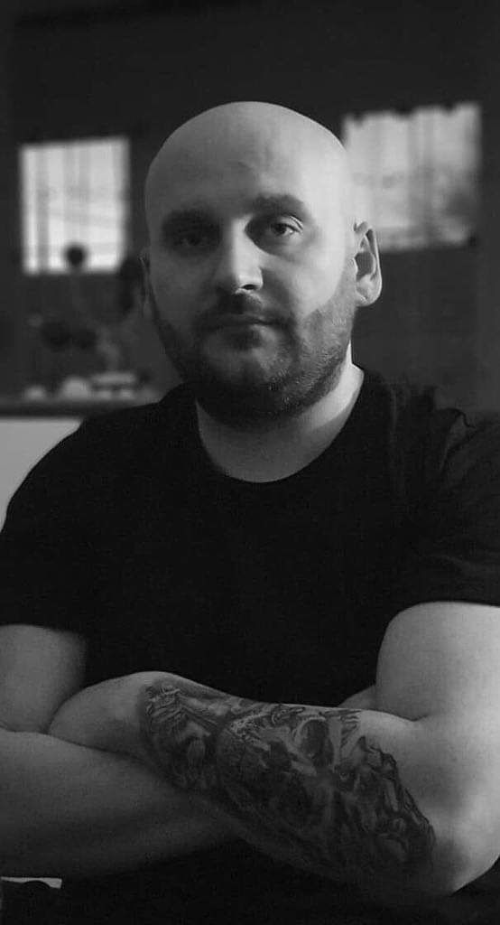 a man with narben tattoos sitting at a table, frankfurt, germany