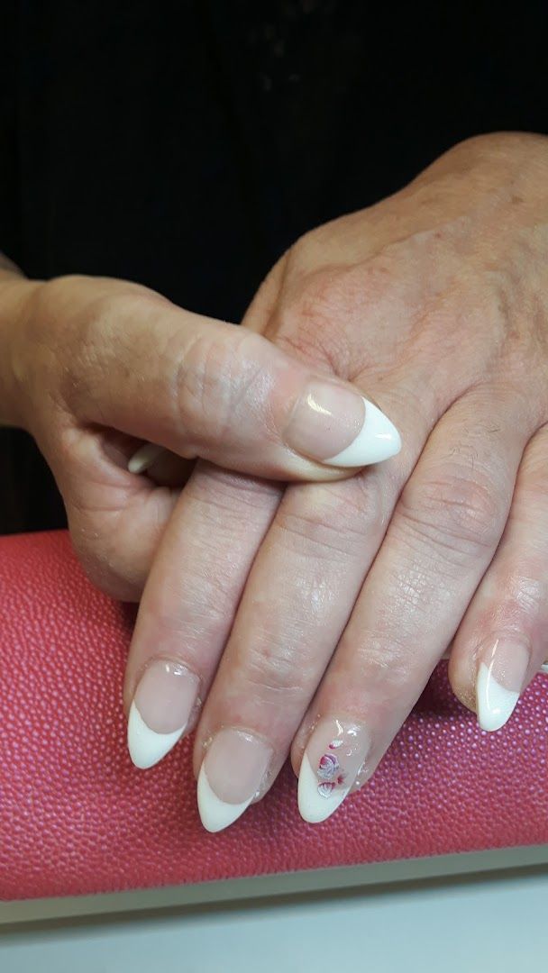 a woman's hands with white nails and a pink purse