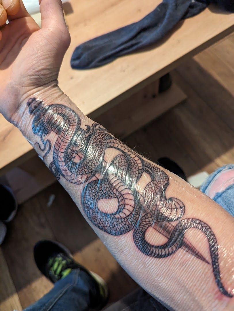 a person holding a cigarette and a snake narben tattoo, ammerland, germany