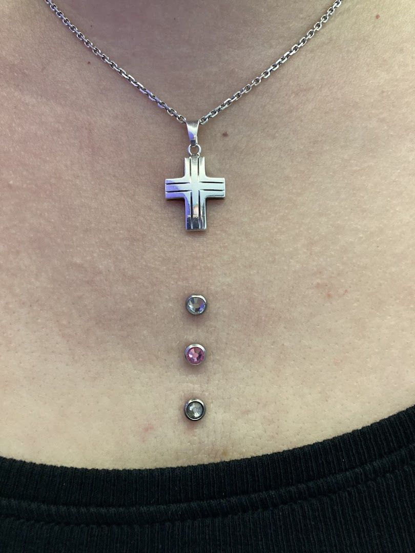 a woman wearing a necklace with a cross and two diamonds