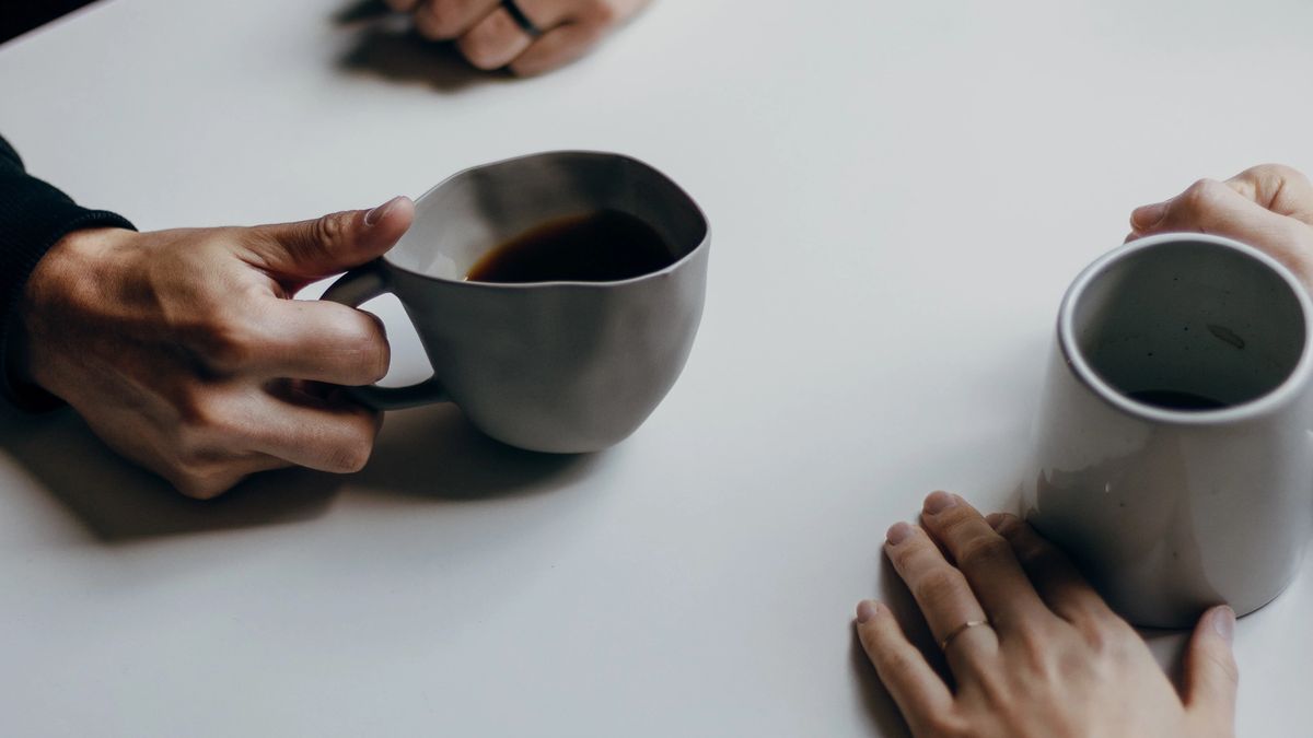 2 people drinking coffee and having a conversation