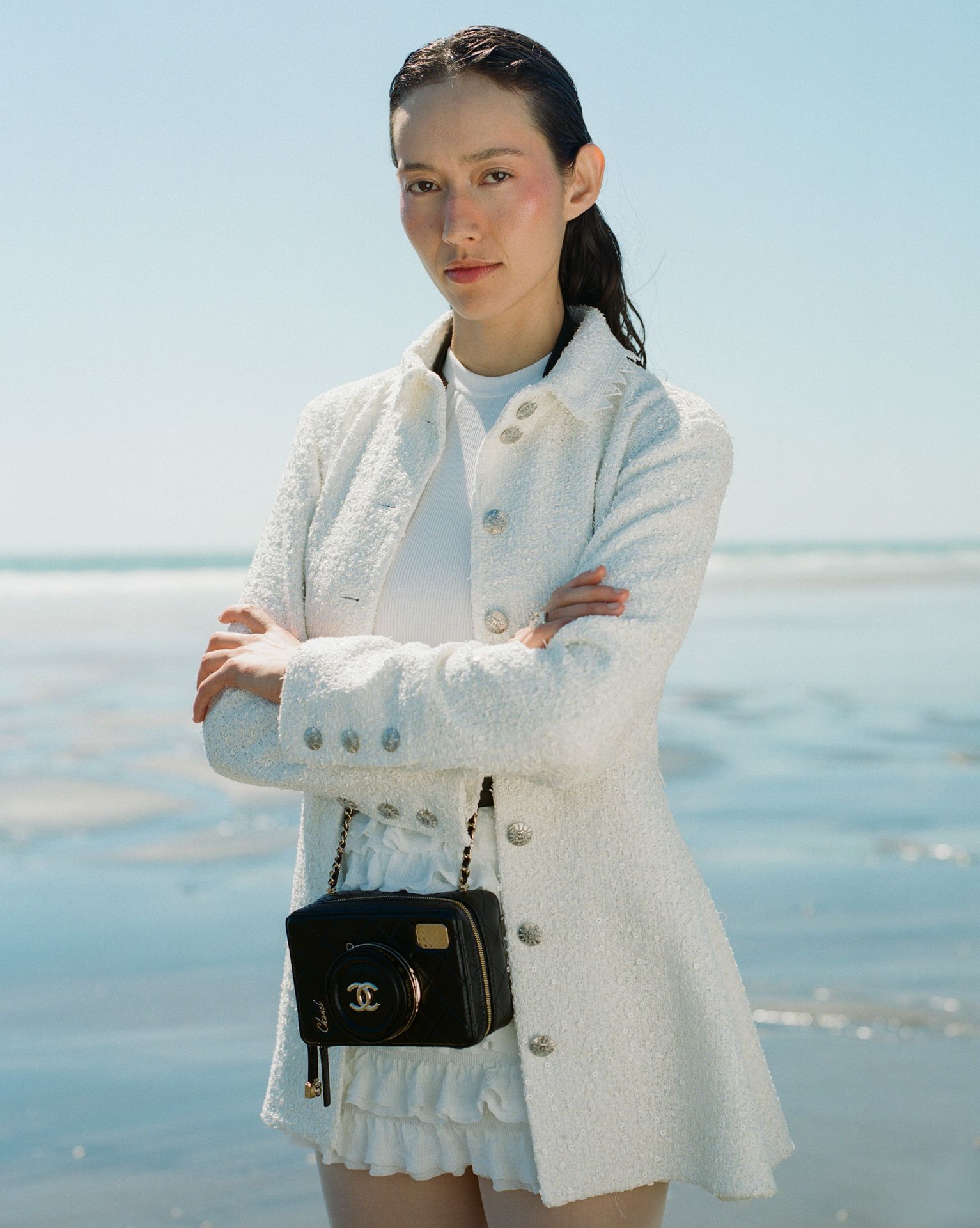 a woman wearing a colorful floral shirt and skirt is standing on a beach .