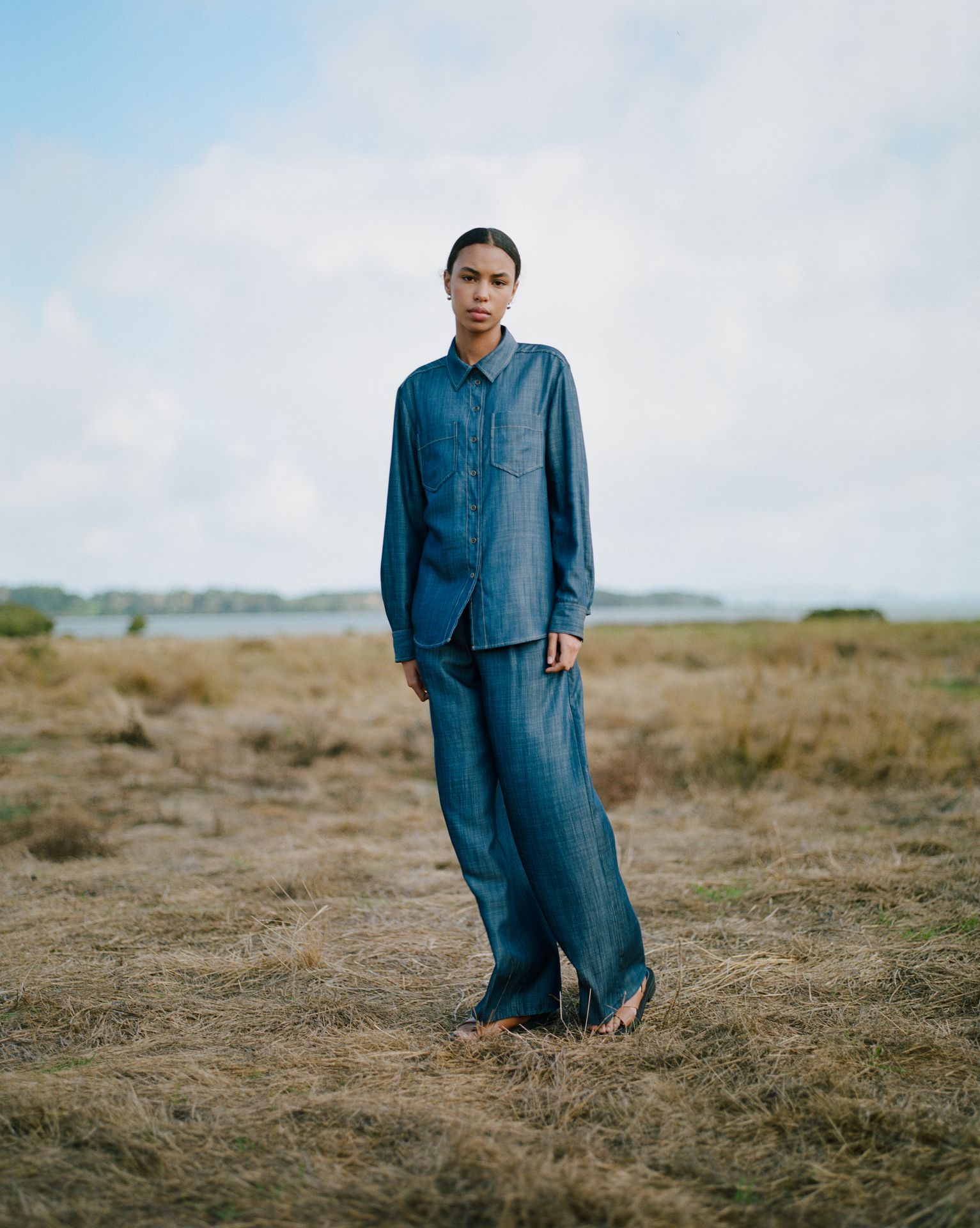 a woman in a plaid shirt is sitting in a field .