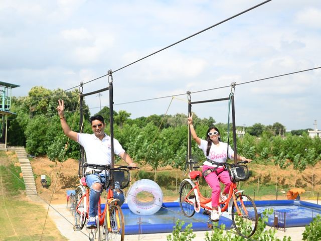 Two people riding cycles on a high rope across a pool during an adventure activity at Rangmanch Farms, an outdoor outing venue in Gurugram near Delhi