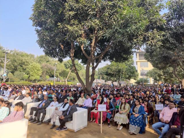 Large company gathering seated outdoors under shade trees — outdoor corporate event venue for big teams, Rangmanch Farms, Gurugram
