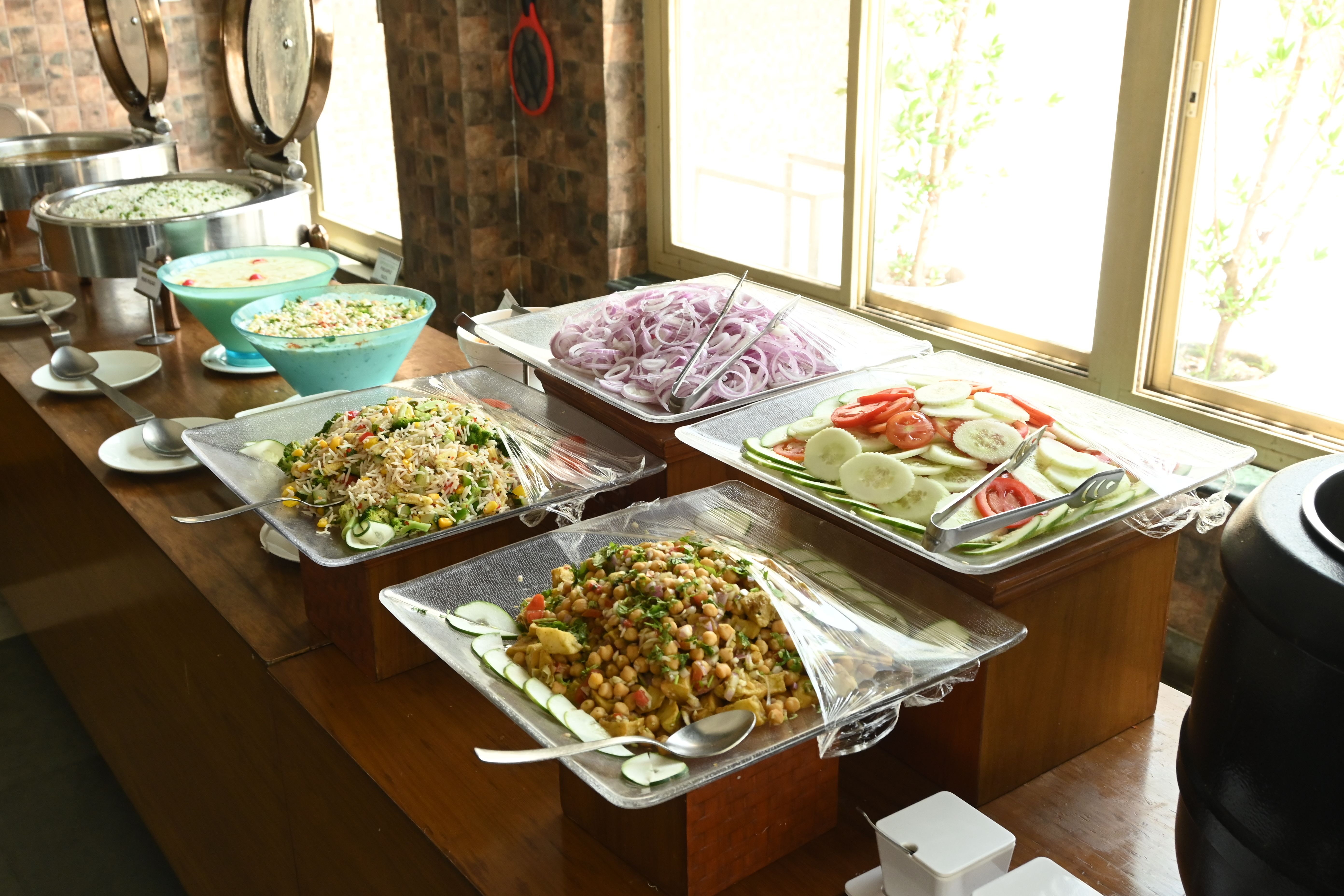 Salad counter with sliced onions, cucumber, tomato and chickpea salad on the buffet at Rangmanch Farms, an event and corporate outing venue in Gurugram near Delhi