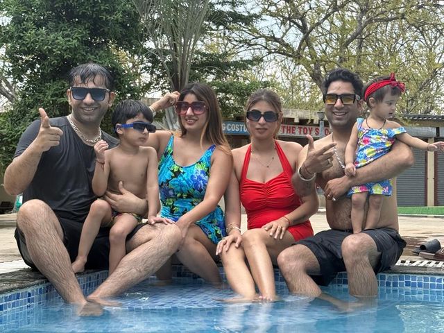 Families with children in swimwear sitting at the edge of the outdoor swimming pool during a day outing at Rangmanch Farms in Gurugram near Delhi