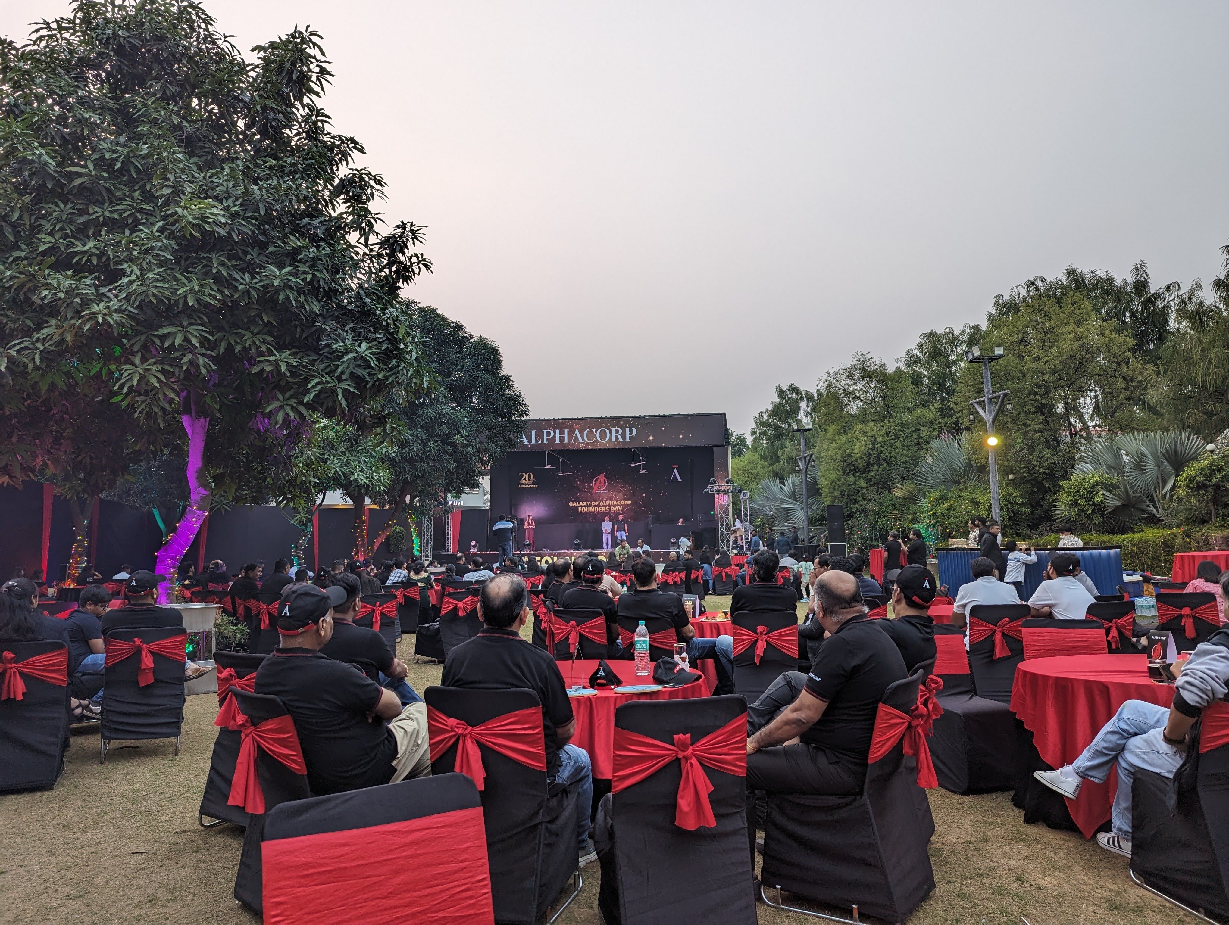 Employees watching the annual day stage programme at dusk — corporate offsite venue in Gurugram, 30 minutes from Delhi