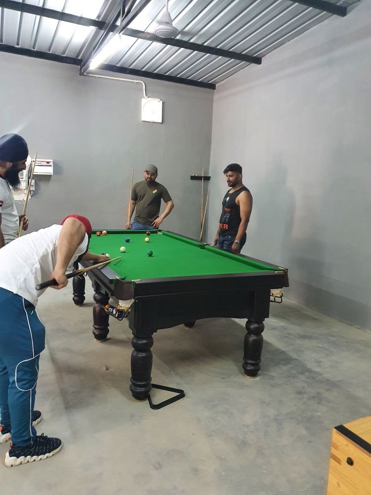 Guests playing pool on an indoor billiards table in the games room at Rangmanch Farms, a corporate outing and team offsite venue in Gurugram near Delhi