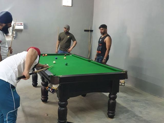 Guests playing pool on an indoor billiards table in the games room at Rangmanch Farms, a corporate outing and team offsite venue in Gurugram near Delhi