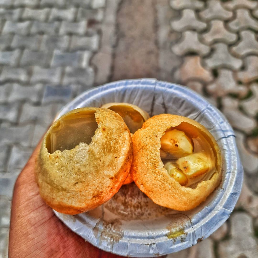 A hand holding a bowl of filled golgappas from the chaat counter at Rangmanch Farms, an outdoor event venue in Gurugram near Delhi
