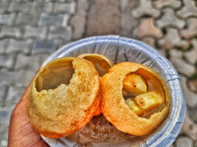 A hand holding a bowl of filled golgappas from the chaat counter at Rangmanch Farms, an outdoor event venue in Gurugram near Delhi