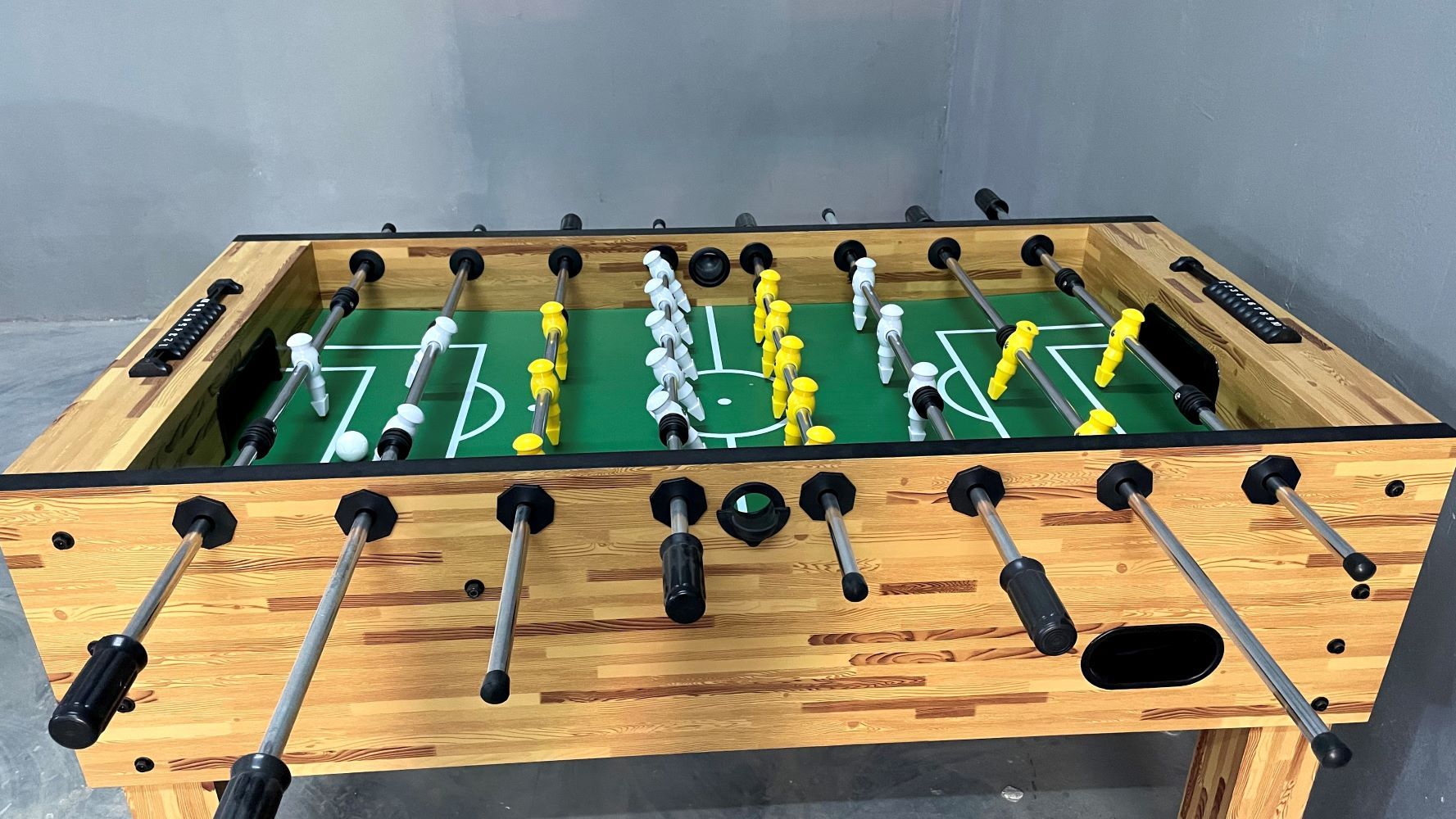 Wooden foosball table with yellow and white players set up for indoor games at Rangmanch Farms, a corporate offsite and day outing venue in Gurugram near Delhi