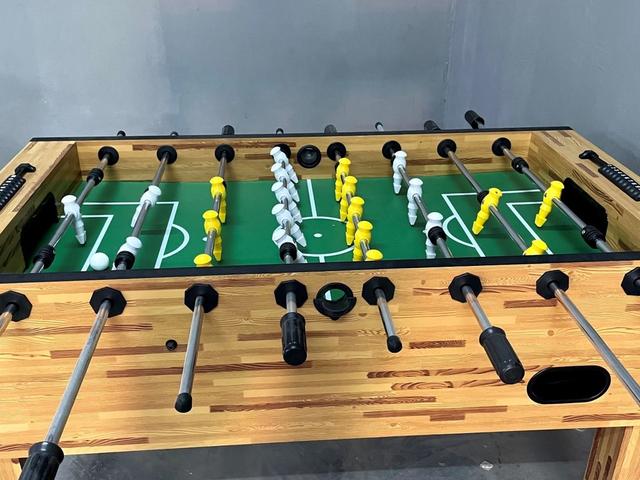 Wooden foosball table with yellow and white players set up for indoor games at Rangmanch Farms, a corporate offsite and day outing venue in Gurugram near Delhi