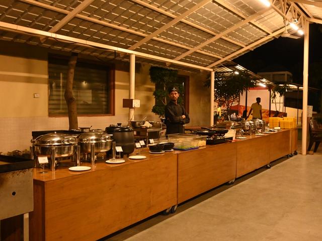Staff attending a buffet counter with chafing dishes and a live counter during an evening dinner at Rangmanch Farms, an outdoor event venue in Gurugram near Delhi