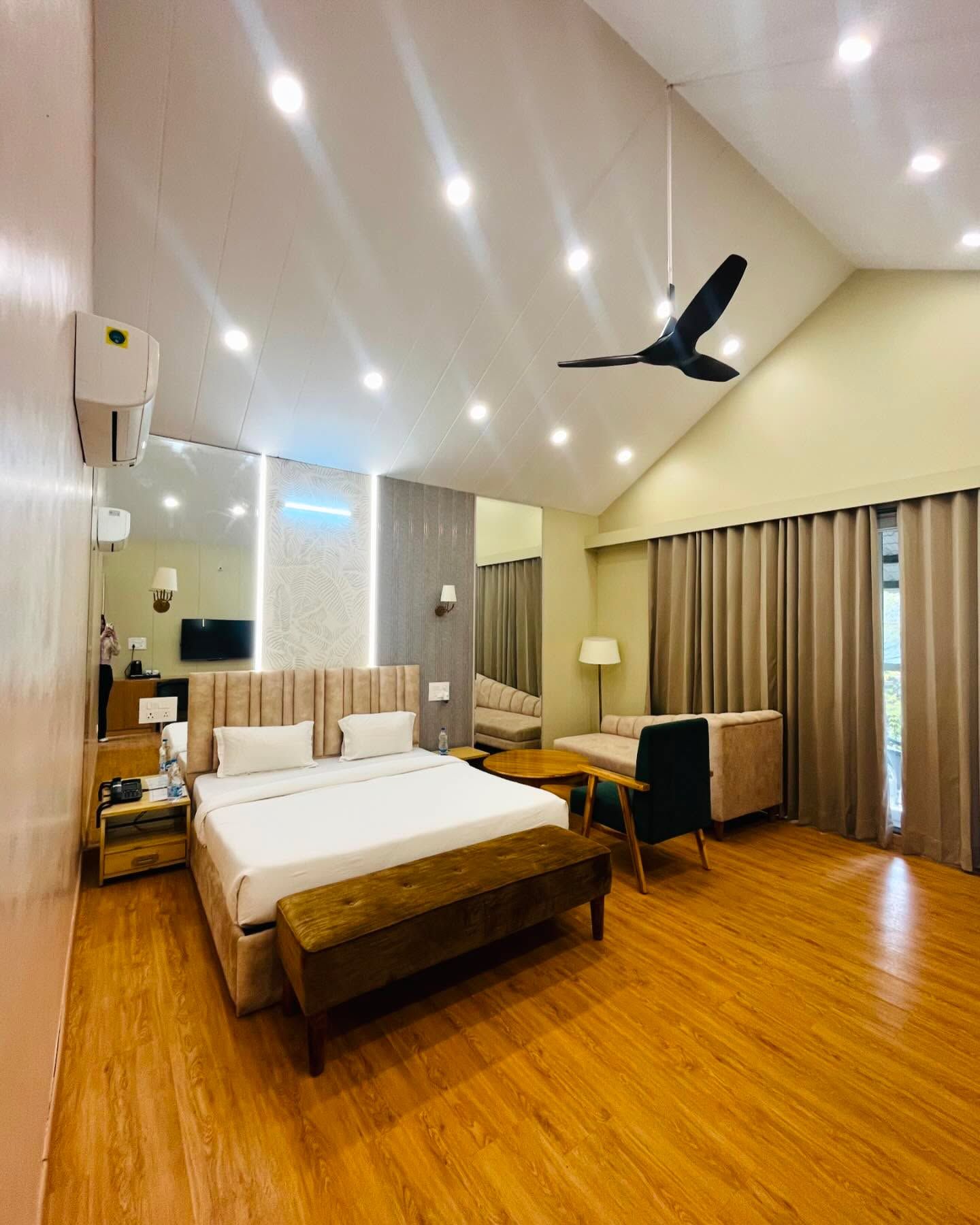 Air-conditioned guest room with a double bed, seating and wooden flooring for overnight stays at Rangmanch Farms in Gurugram, near Delhi