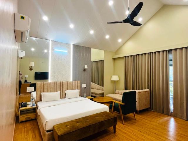 Air-conditioned guest room with a double bed, seating and wooden flooring for overnight stays at Rangmanch Farms in Gurugram, near Delhi